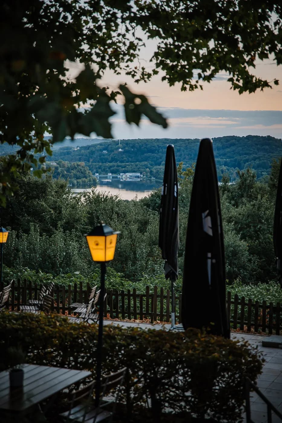 Sonnenuntergang über dem Baldeneysee mit Laterne und Sonnenschirm-Silhouette