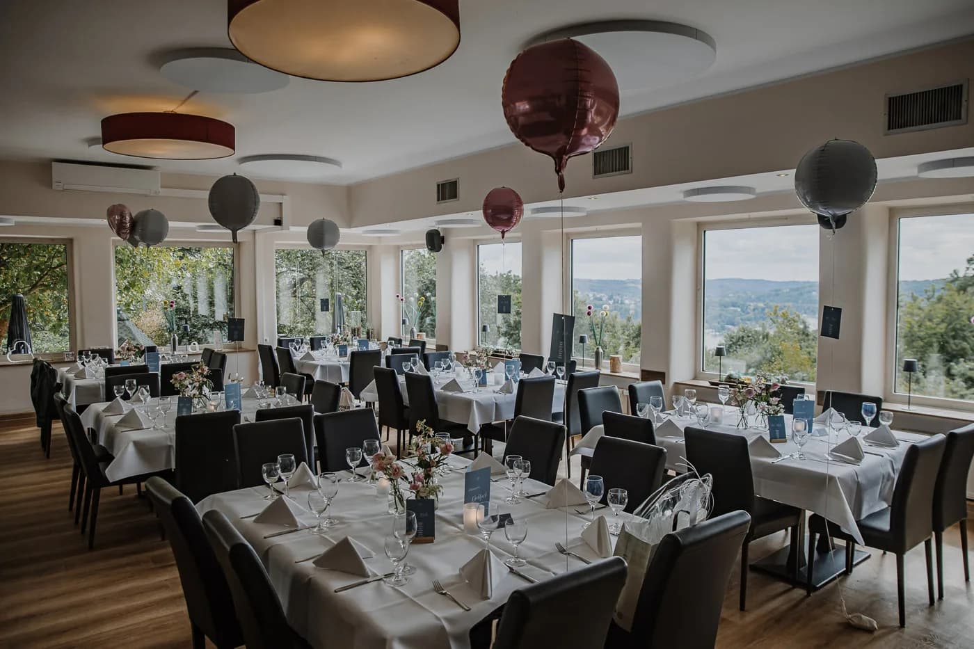 Festtafel im Restaurant mit Burgund- und Grau-Ballons und Panoramablick auf das Ruhrtal